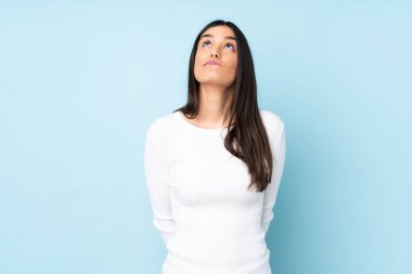 Genç beyaz kadın mavi arka planda izole edilmiş ve yukarı bakıyor.
