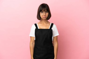 Soyutlanmış pembe arka planda garsonun üzgün bir ifadesi var.