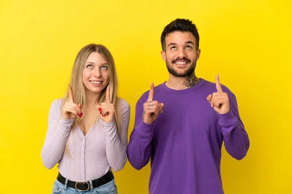 Casal Jovem Sobre Fundo Amarelo Isolado Apontando Para Cima Com — Fotografia de Stock