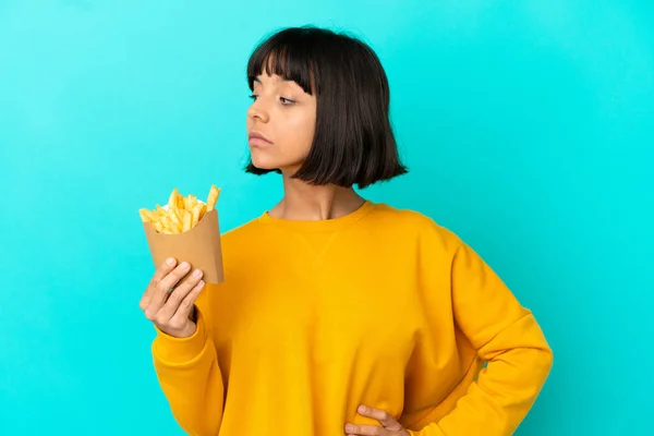 Joven Morena Sosteniendo Chips Fritos Sobre Fondo Azul Aislado Mirando — Foto de Stock