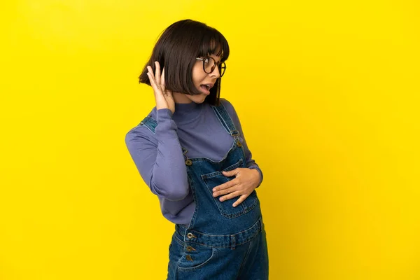 Jovem Grávida Sobre Fundo Amarelo Isolado Ouvindo Algo Colocando Mão — Fotografia de Stock