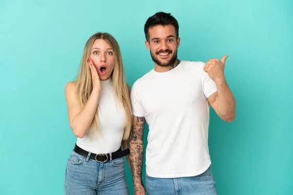 Junges Paar Auf Isoliertem Blauem Hintergrund Zeigt Mit Dem Finger — Stockfoto