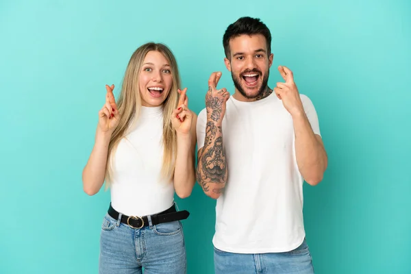 Casal Jovem Sobre Fundo Azul Isolado Com Dedos Cruzando — Fotografia de Stock