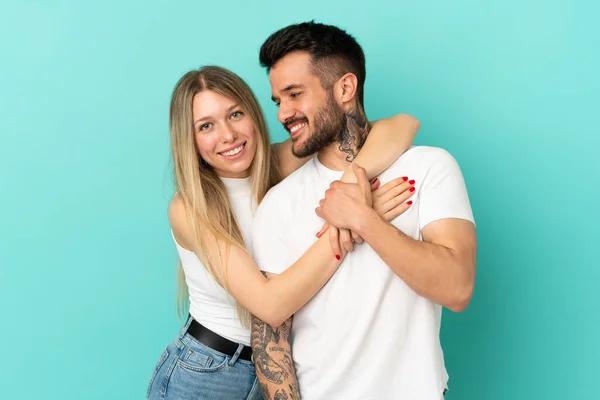 离群索居的蓝色背景上的一对年轻夫妇笑着拥抱 — 图库照片