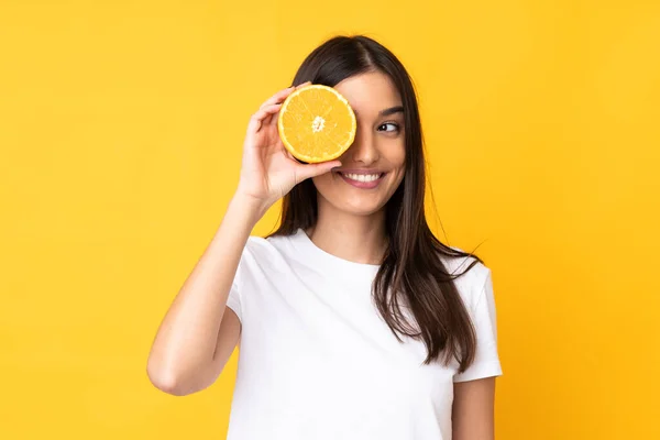 Junge Kaukasische Frau Hält Eine Orange Über Einem Isolierten Gelben — Stockfoto