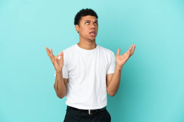 Genç Afrikalı Amerikalı bir adam mavi arka planda izole edilmiş.