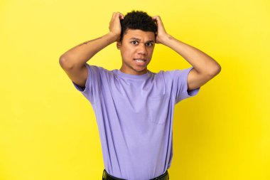 Sarı arka planda izole edilmiş genç Afrikalı Amerikalı adam gergin hareketler yapıyor.