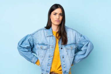 Kafkasyalı genç bir kadın mavi arka planda izole edilmiş, kızgın.