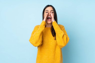 Beyaz bir kadın mavi arka planda izole edilmiş bağırıyor ve bir şeyler söylüyor.