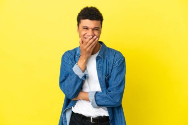 Sarı arka planda izole edilmiş genç Afrikalı Amerikalı adam mutlu ve gülümsüyor.