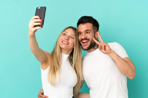 Pareja Joven Sobre Fondo Azul Aislado Haciendo Una Selfie Con —  Fotos de Stock