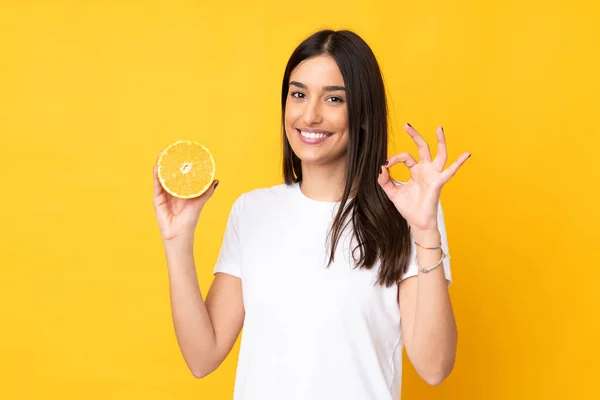 Ung Kaukasiska Kvinna Som Håller Orange Isolerad Gul Bakgrund Visar — Stockfoto