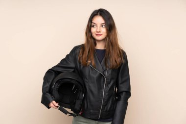 Motosiklet kasklı kadın bej arka planda izole edilmiş duruyor ve yan tarafa bakıyor.