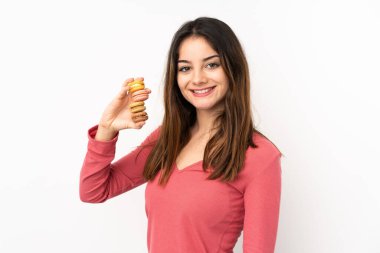 Pembe arka planda soyutlanmış beyaz bir kadın. Renkli Fransız kurabiyeleri tutuyor ve gülümsüyor.