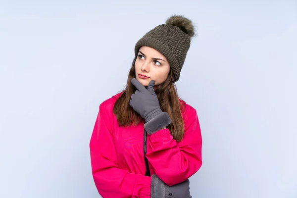 Νεαρή Κοπέλα Χειμερινό Καπέλο Απομονωμένη Μπλε Φόντο Αμφιβολίες Και Έκφραση — Φωτογραφία Αρχείου