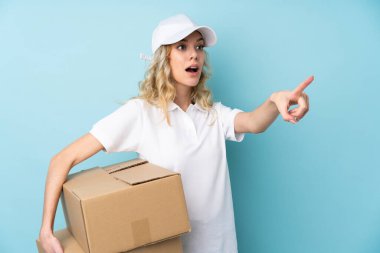 Genç teslimatçı kadın mavi arka planda izole edilmiş.
