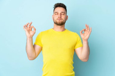 Rus yakışıklı adam Zen pozunda mavi arka planda izole edilmiş.