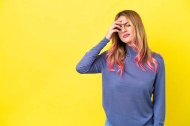 Sarı arka planda, baş ağrısı olan genç bir kadın.