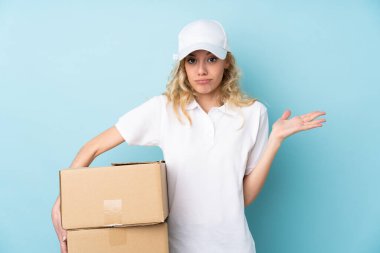 Mavi arka planda izole edilmiş genç teslimatçı kadın.