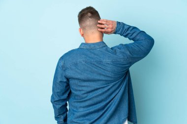 Rus yakışıklı adam mavi arka planda izole edilmiş ve düşünüyor.