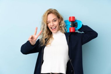 Mavi arka planda, zafer jesti yapan genç sarışın kadın.