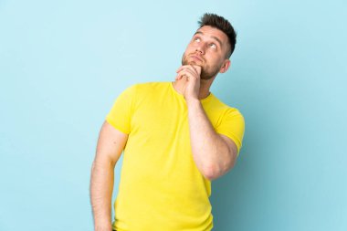 Rus yakışıklı adam mavi arka planda izole edilmiş ve yukarı bakıyor.