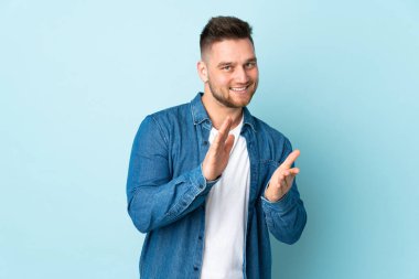 Mavi arka planda izole edilmiş Rus yakışıklı bir adam bir konferanstan sonra alkışlıyor.