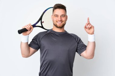 Beyaz arka planda izole edilmiş Rus yakışıklı adam tenis oynuyor ve yukarı işaret ediyor.