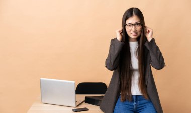 İş yerindeki Çinli iş kadını hayal kırıklığına uğramış ve kulaklarını tıkamış.