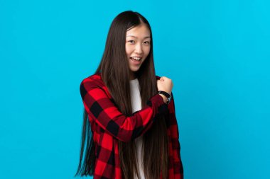 Genç Çinli kız mavi arka planda zaferi kutluyor.