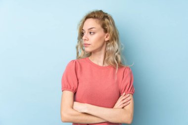 Mavi arka planda izole edilmiş genç sarışın kadın.