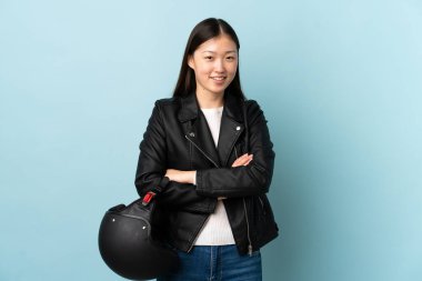 Mavi arka planda motosiklet kaskı tutan Çinli kadın gülüyor.