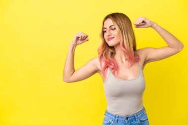 Sarı arka planda kalan genç bir kadın güçlü bir jest yapıyor.
