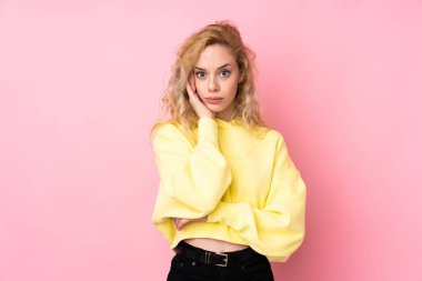 Pembe arka planda izole edilmiş sweatshirt giyen genç sarışın kadın sağa bakarken şaşırmış ve şok olmuştu.