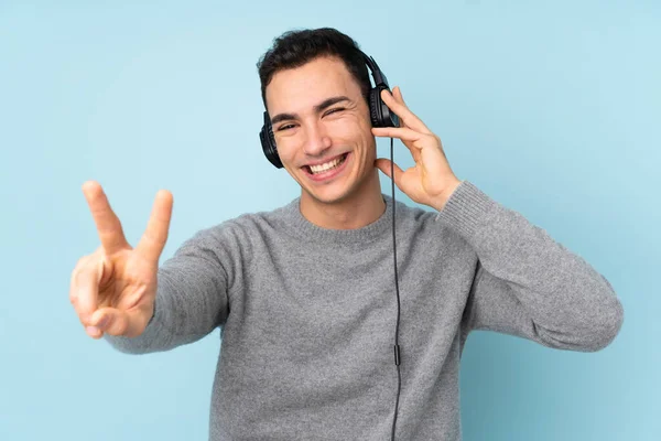 Jonge Kaukasische Knappe Man Geïsoleerd Blauwe Achtergrond Luisteren Muziek Zingen — Stockfoto