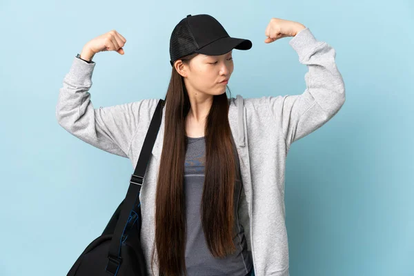 年轻的中国女子 身披运动包 身披深蓝色背景 做着强有力的手势 — 图库照片