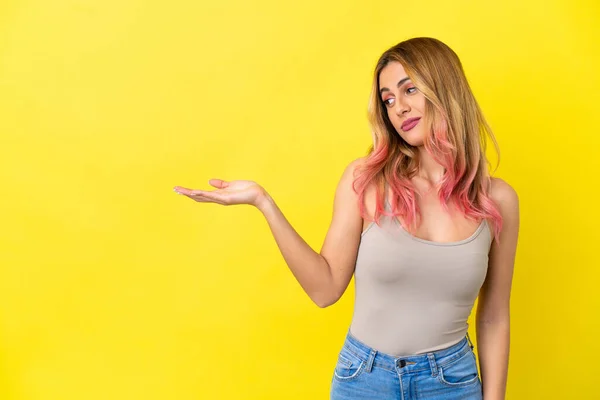 Mujer Joven Sobre Fondo Amarillo Aislado Sosteniendo Copyspace Con Dudas — Foto de Stock