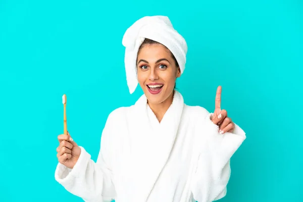 Young Woman Bathrobe Brushing Teeth Isolated Blue Background Pointing Great — Stock Photo, Image