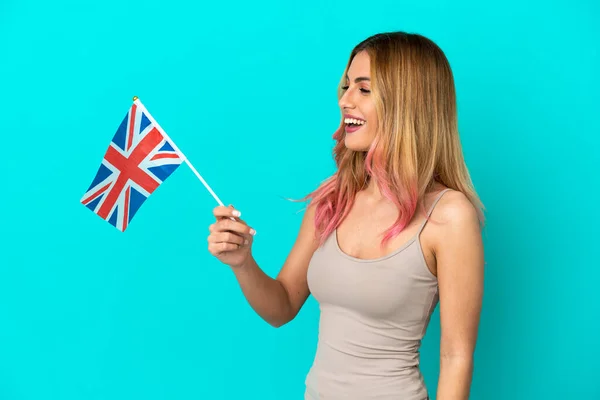 イギリス国旗を掲揚する若い女性が幸せな表情で孤立した青を背景に — ストック写真