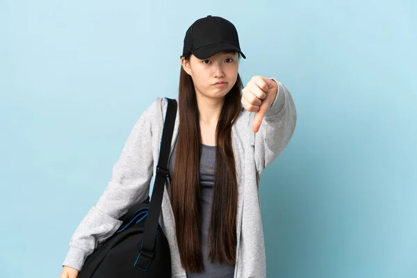 年轻的中国女子体育运动员 背着运动包 蓝色背景 带着负面表情垂手可得 — 图库照片