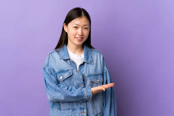 年轻的中国女孩在孤独的紫色背景上展示了一个想法 同时微笑着看着 — 图库照片