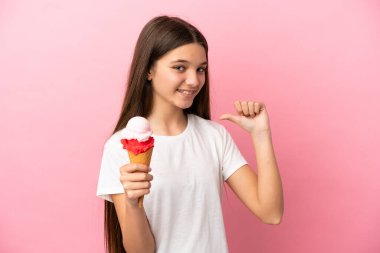 Kornet dondurması ile izole edilmiş pembe arka planda gururlu ve kendini beğenmiş küçük bir kız.