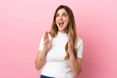 Pembe arka planda yalıtılmış beyaz bir kadın. Sürpriz bir yüz ifadesi var.