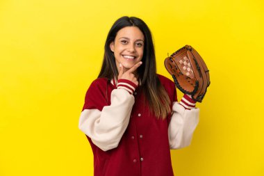 Beyzbol oynayan beyaz bir kadın sarı arka planda izole edilmiş mutlu ve gülümsüyor.