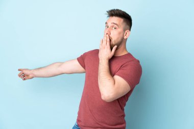 İzole edilmiş arka planı olan yakışıklı Rus bir adam sürpriz bir ifadeyle işaret ederken