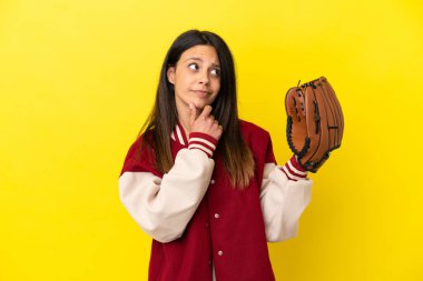 Beyzbol oynayan beyaz bir kadın sarı arka planda izole edilmiş, kuşkuları var.