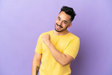 Mor arka planda izole edilmiş genç beyaz bir adam zaferi kutluyor.