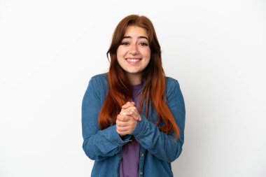 Genç kızıl saçlı kadın beyaz arka planda yalnız gülüyor.