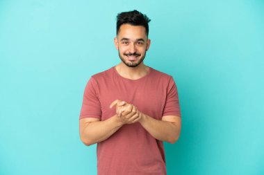 Kafkasyalı genç adam mavi arka planda tek başına gülüyor.