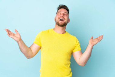 Rus yakışıklı adam mavi arka planda izole edilmiş, çok gülümsüyor.